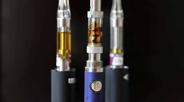 Vape pens and cartridges with a dark background.